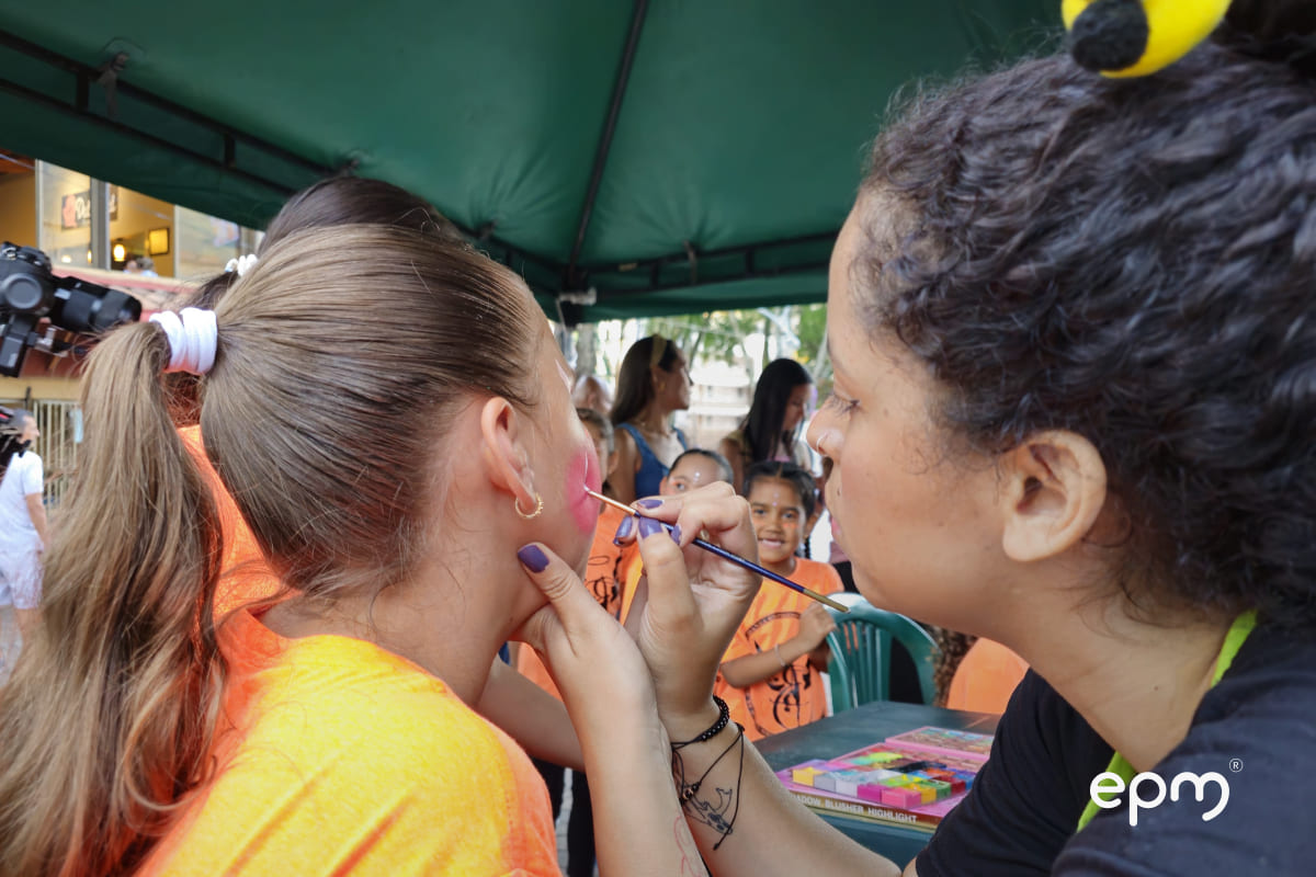Fotografía de una mujer pintando la cara de una niña