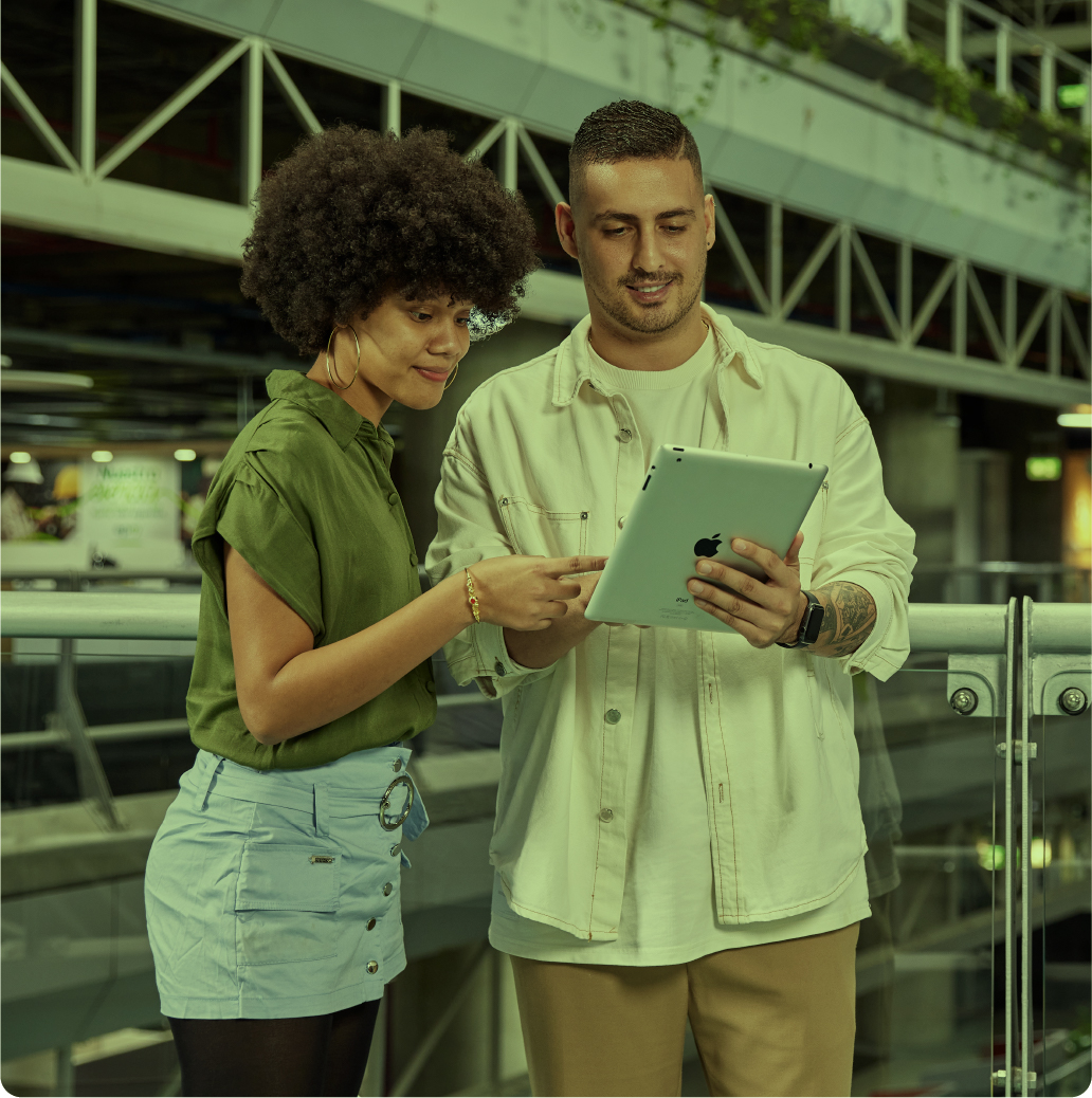 Hombre y mujer sonriendo, revisando pantalla de tablet