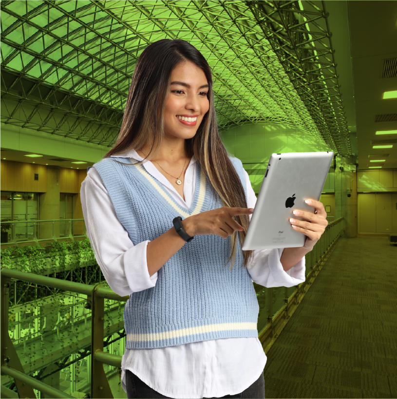Mujer sonriente interactuando con una tableta en un espacio institucional moderno.