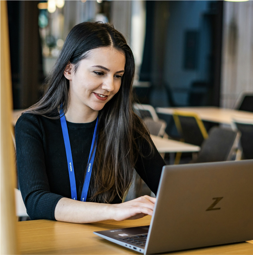 Mujer joven trabajando en un computador portátil en un entorno de oficina.