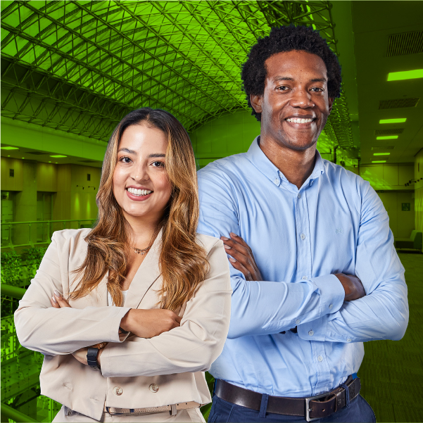 Hombre y mujer sonriendo, con los brazos cruzados, en un espacio institucional iluminado.