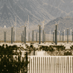 Parque eólico en zona desértica con múltiples aerogeneradores en funcionamiento, al fondo montañas áridas; representa la apuesta de EPM por la energía renovable y la transición energética sostenible