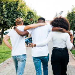 Tres personas caminando abrazadas por un sendero rodeado de árboles, simbolizando inclusión, diversidad, amistad y el compromiso de EPM con las comunidades