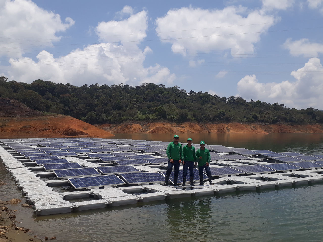 Trabajadores sobre unos paneles solares que están flotando en un río