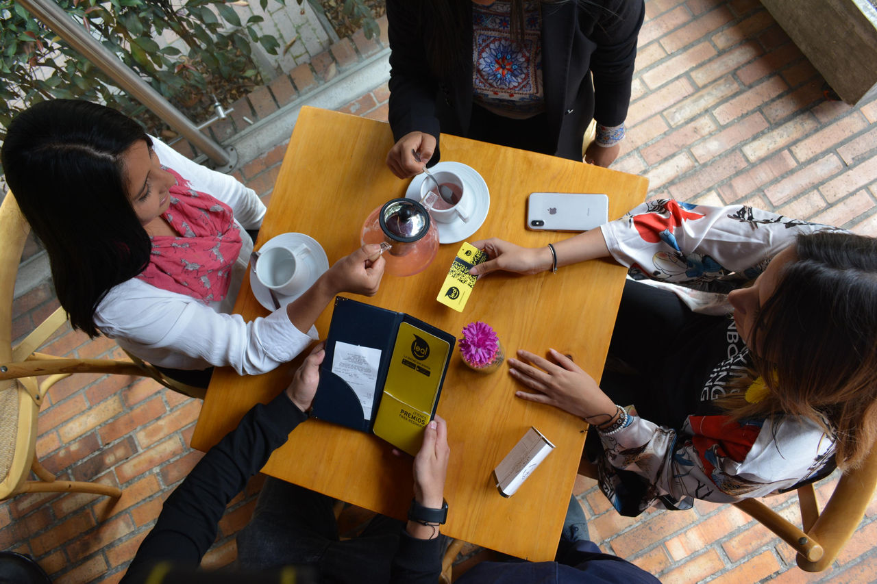 Grupo de cuatro personas en reunión sobre sostenibilidad energética de EPM, con materiales impresos y bebidas en una mesa de madera