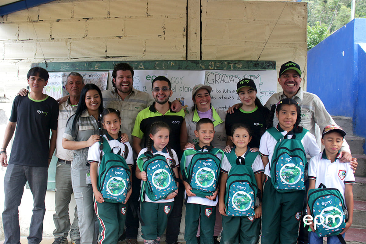 Adultos y niños posando juntos con kits escolares en un ambiente festivo, resaltando el apoyo a la educación en la comunidad de Ituango.