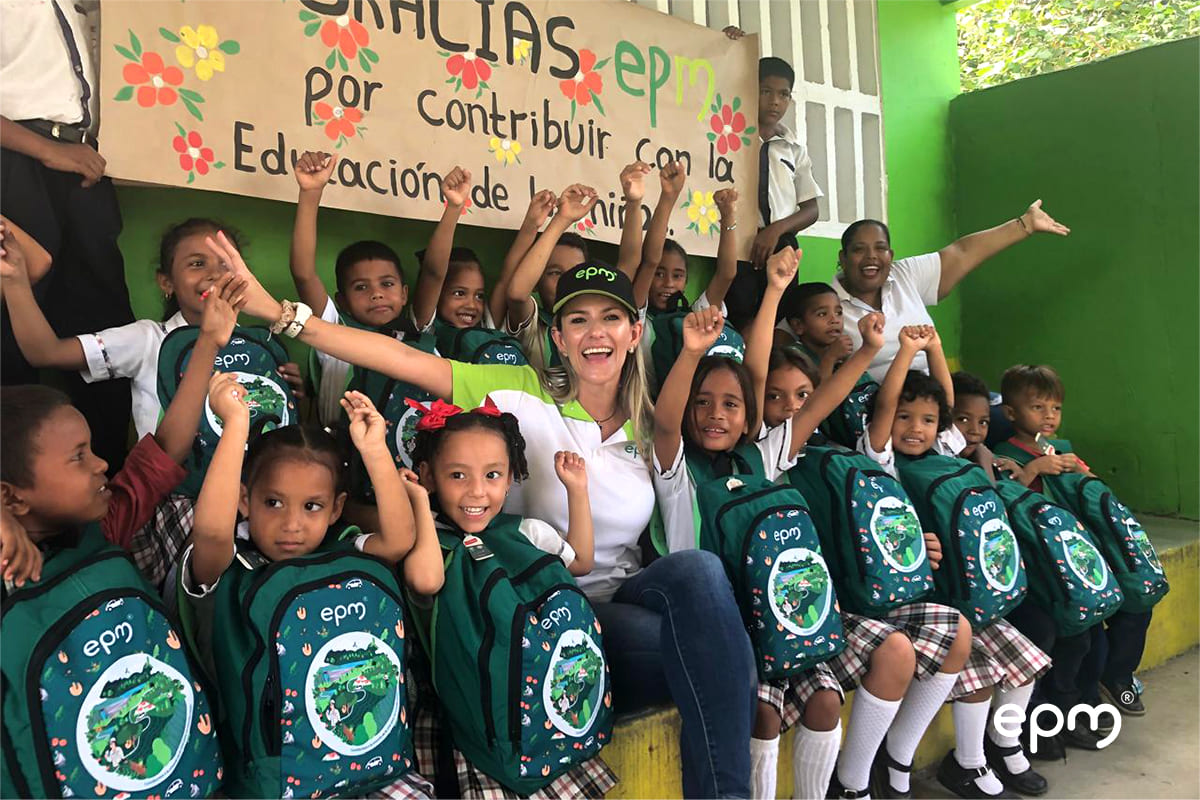 Niños con kits escolares levantando sus manos en señal de triunfo, celebrando la iniciativa de EPM para favorecer la educación en la región de Ituango.