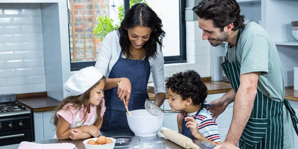 Familia cocinando junta en la cocina con sus hijos pequeños.