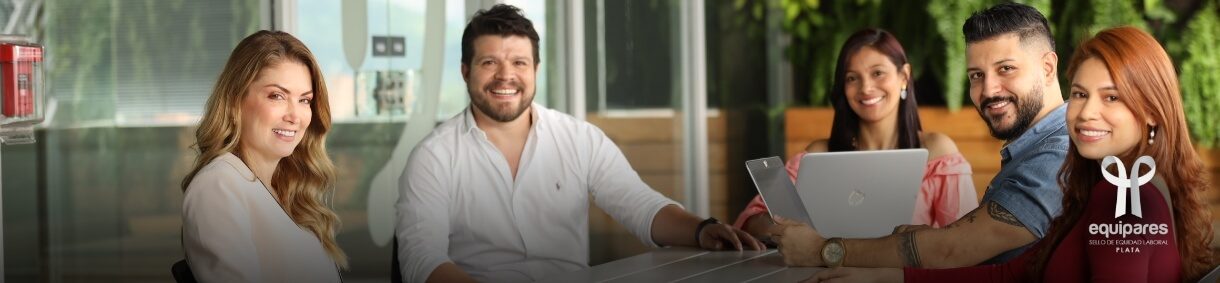 Grupo diverso de personas sonriendo mientras trabajan con computadoras portátiles