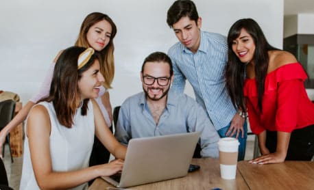 Ofertas abiertas a la comunidad y públicos específicos, el acceso a esta información tiene una imagen de varias personas que sonríen mientras observan la pantalla de un portátil.