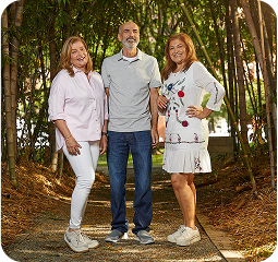 Grupo de dos mujeres y un hombre posando y sonriendo