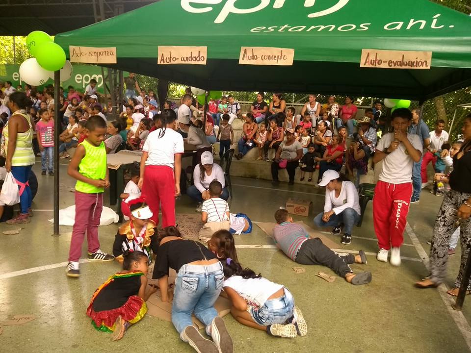 Fotografía de Varios niños debajo de una carpa verde de EPM participando en una actividad