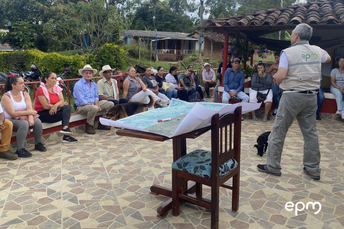 Fotografía de trabajador de EPM conversando con los ciudadanos sobre el Proyecto Carrieles EPM, les presenta los planos del proyecto