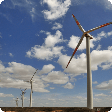 Aerogeneradores blancos en funcionamiento sobre un campo verde, generando energía eólica bajo un cielo azul despejado