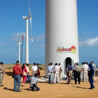 Grupo de técnicos y visitantes inspecciona la base de un aerogenerador del parque eólico Jepírachi