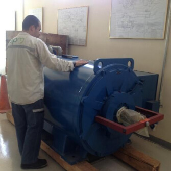 Imagen de un técnico inspeccionando un generador eléctrico azul en el interior de una instalación técnica.