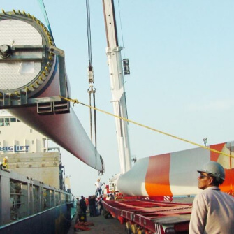 Imagen de el transporte e instalación de una pala de turbina eólica utilizando una grúa en un puerto.
