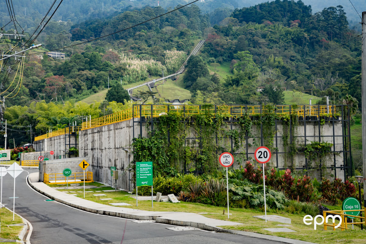 Estructura de concreto con barandas amarillas en la planta La Ayurá, rodeada de vegetación y montañas.