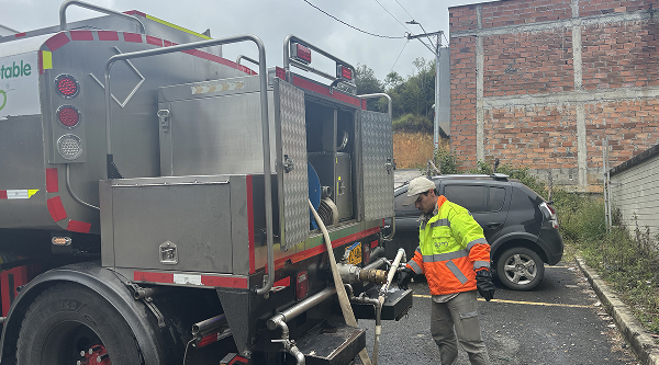 Trabajadores con casco y equipo de seguridad abasteciendo con carrotanque a la comunidad