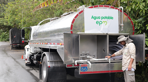 Trabajador manipulando una manguera conectada a un camión cisterna de agua potable con el logotipo de EPM