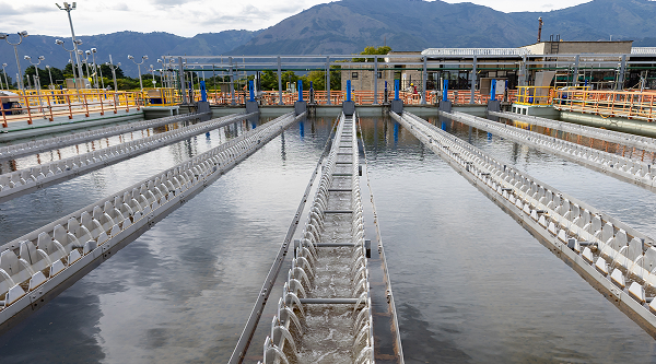 Trabajadores con casco y equipo de seguridad realizando labores de mantenimiento o inspección en una planta industrial al aire libre.