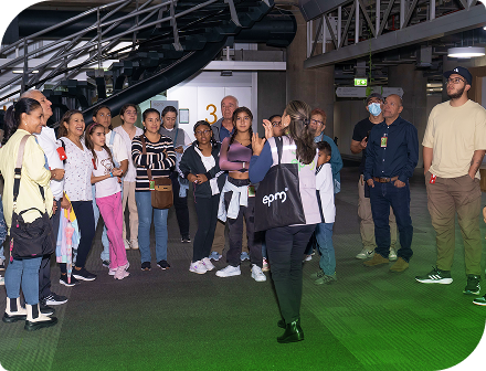 Grupo de visitantes en recorrido guiado dentro de la sede de EPM en Medellín, escuchando una explicación sobre la empresa y sus instalaciones