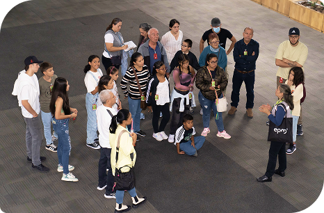 Grupo de visitantes en recorrido guiado dentro de la sede de EPM en Medellín, escuchando a una guía que explica sobre los servicios y la historia de la entidad en un espacio amplio y cerrado