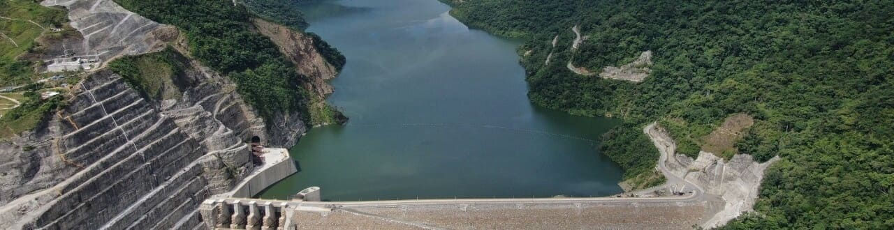 Banner Hidroituango, con imagen de Una vista aérea de la gran represa hidroelectrica ituango y embalse rodeado de exuberantes montañas verdes.