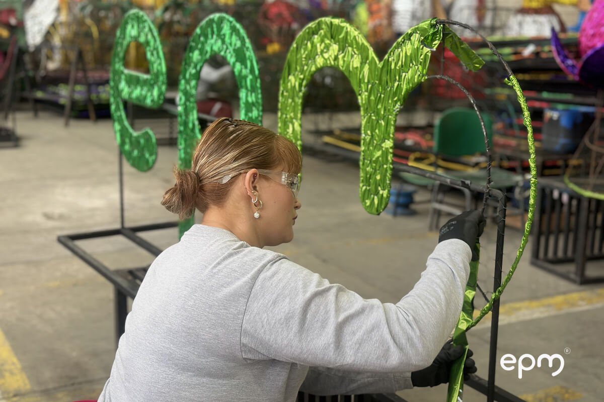 Una artesana trabaja en la creación de una figura luminosa del logo "epm" para los alumbrados navideños.