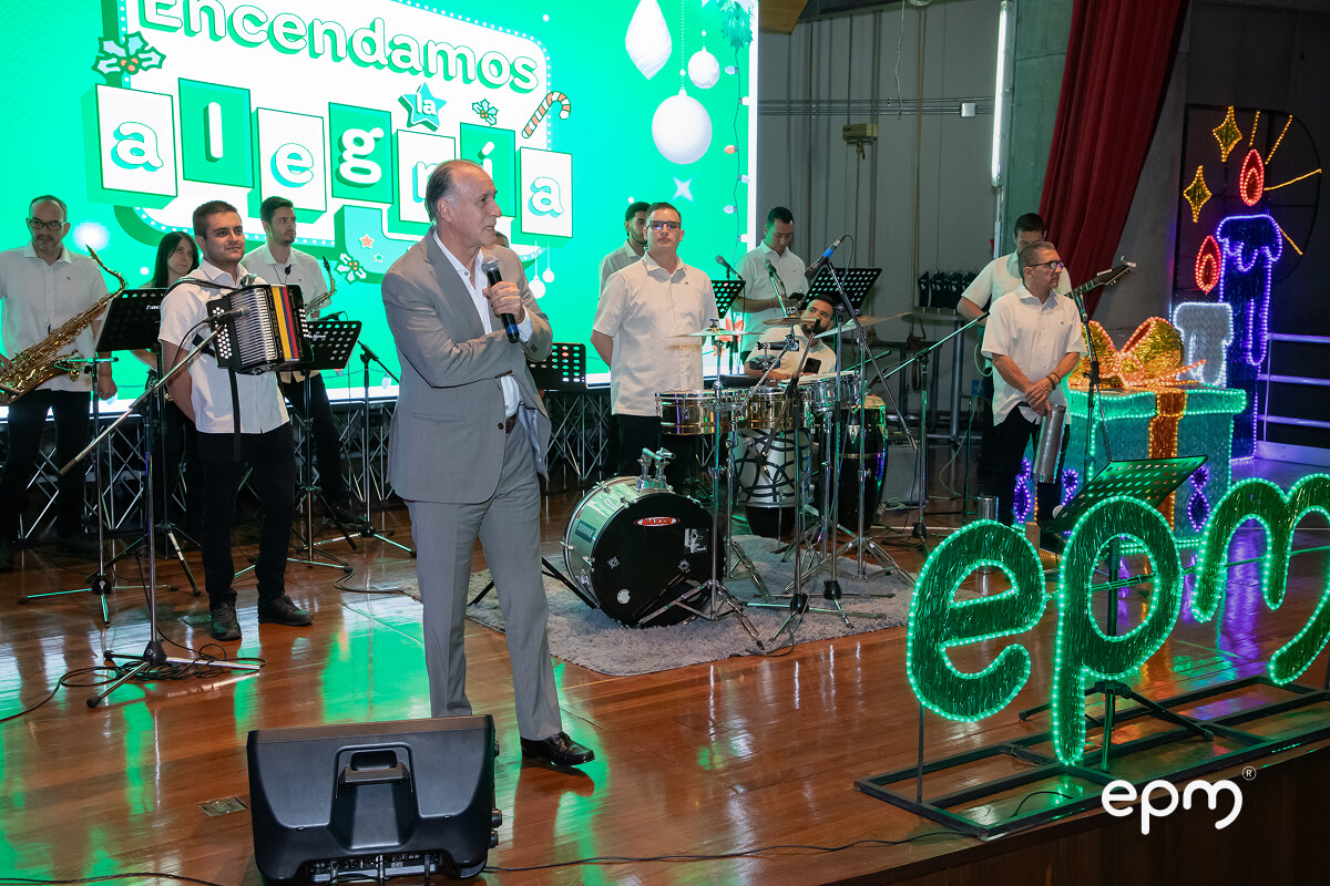 El Gerente de EPM, John Maya Salazar, habla frente a un grupo musical y figuras de luces navideñas que deletrean "epm"