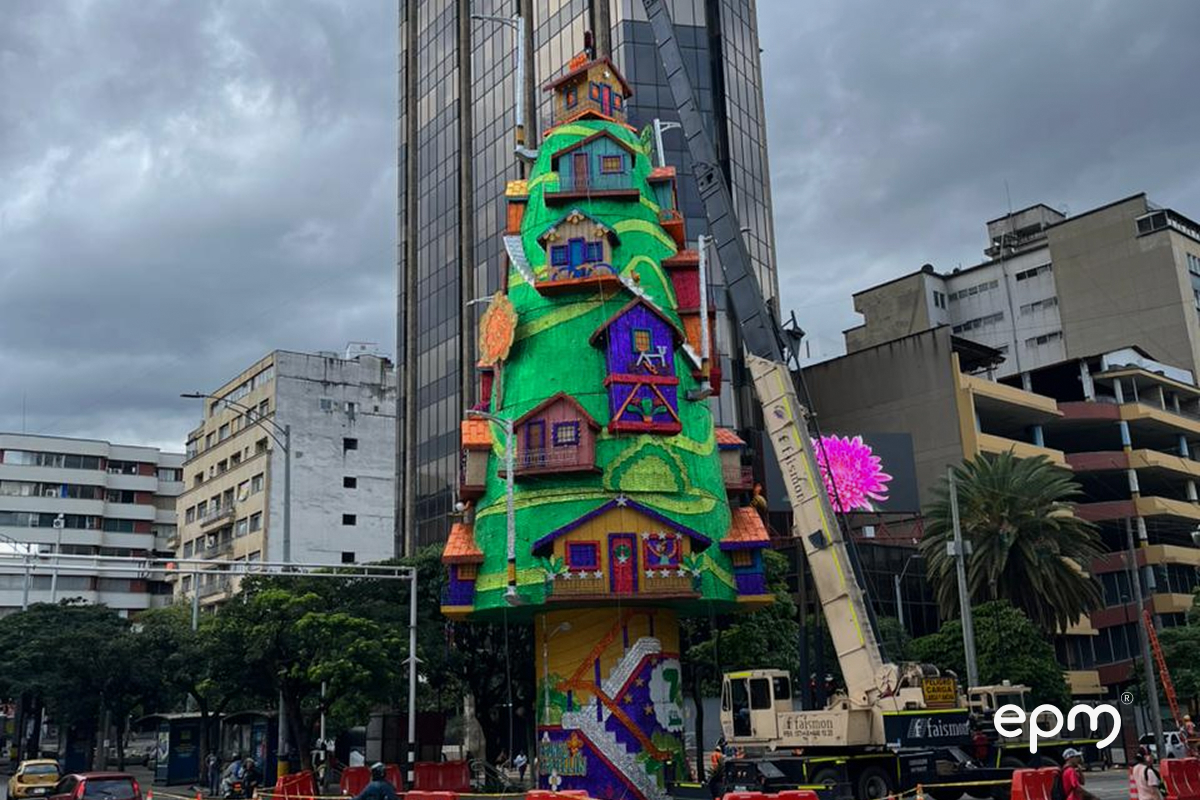 Figura de casa  en color verde para alumbrado de EPM sobre calle del centro de Medellín. Al fondo se observan edificios.
