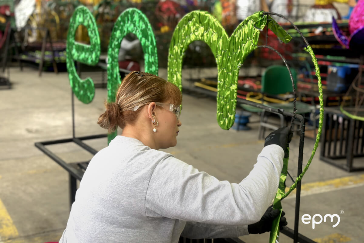 Fotografía tomada a una mujer haciendo el logo EPM para los alumbrados