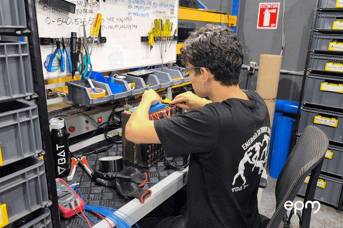 Fotografía de un integrante del equipo de Batx trabaja en el ensamblaje de un dispositivo electrónico en su taller, con herramientas organizadas en el fondo.