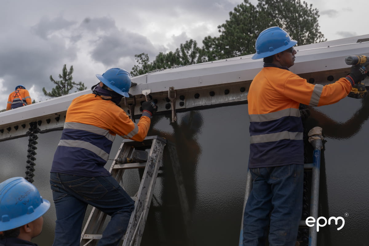Funcionarios de EPM con casco azul y chaleco naranja haciendo labores de mantenimiento en infraestructura de acueducto