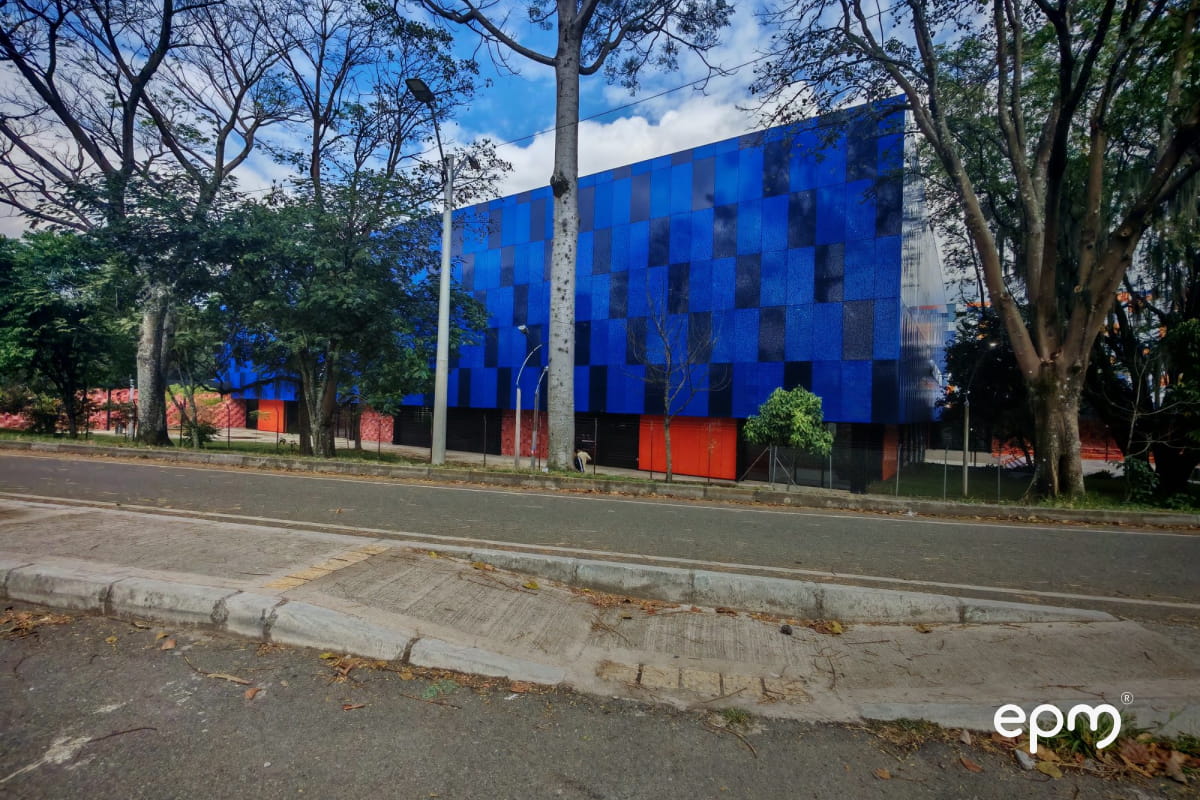 Calle del municipio de Bello con pantalla azul al frente y árboles al costado