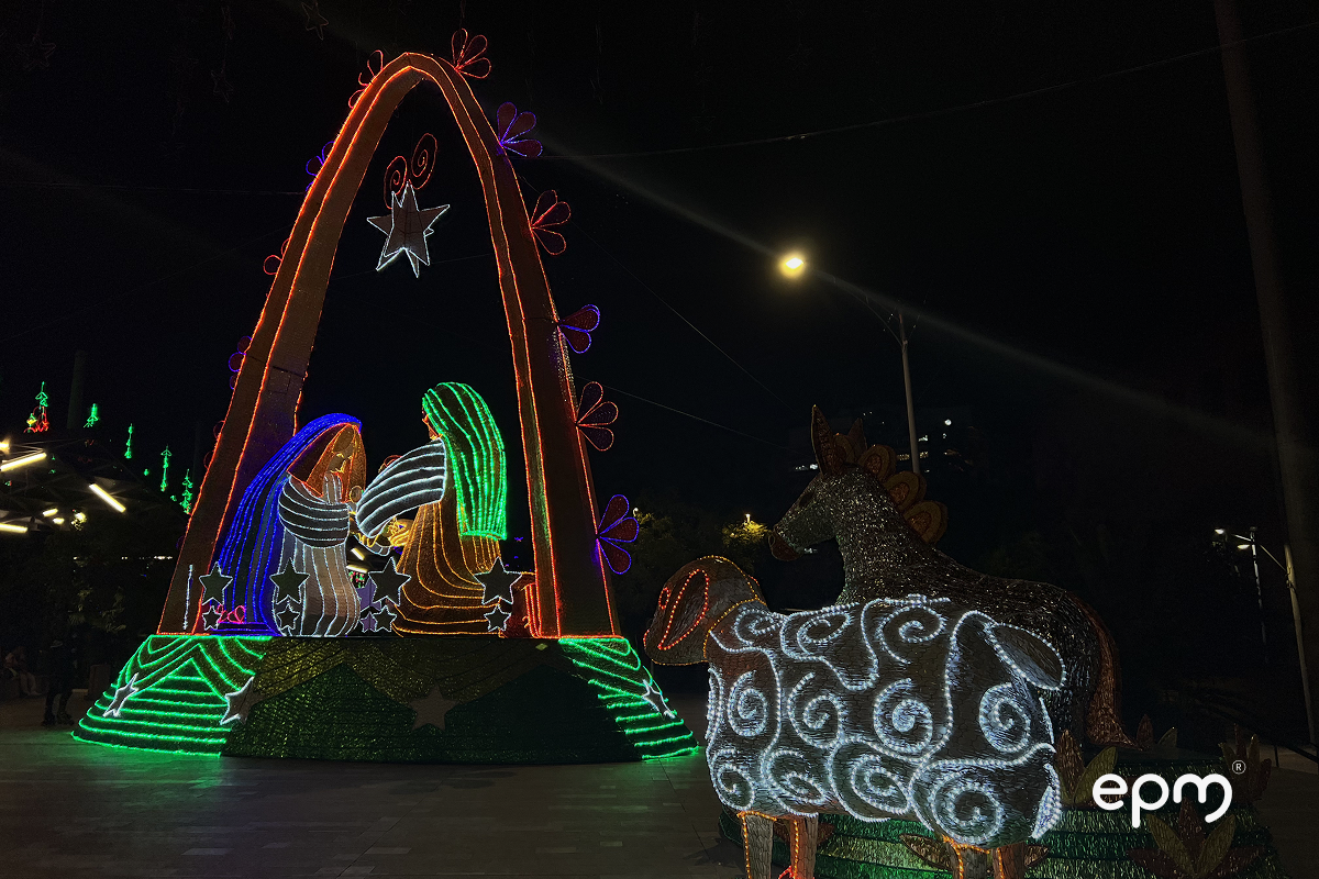 Figura de pesebre navideño de EPM con arco en color rojo y acompañado de animales en color blanco