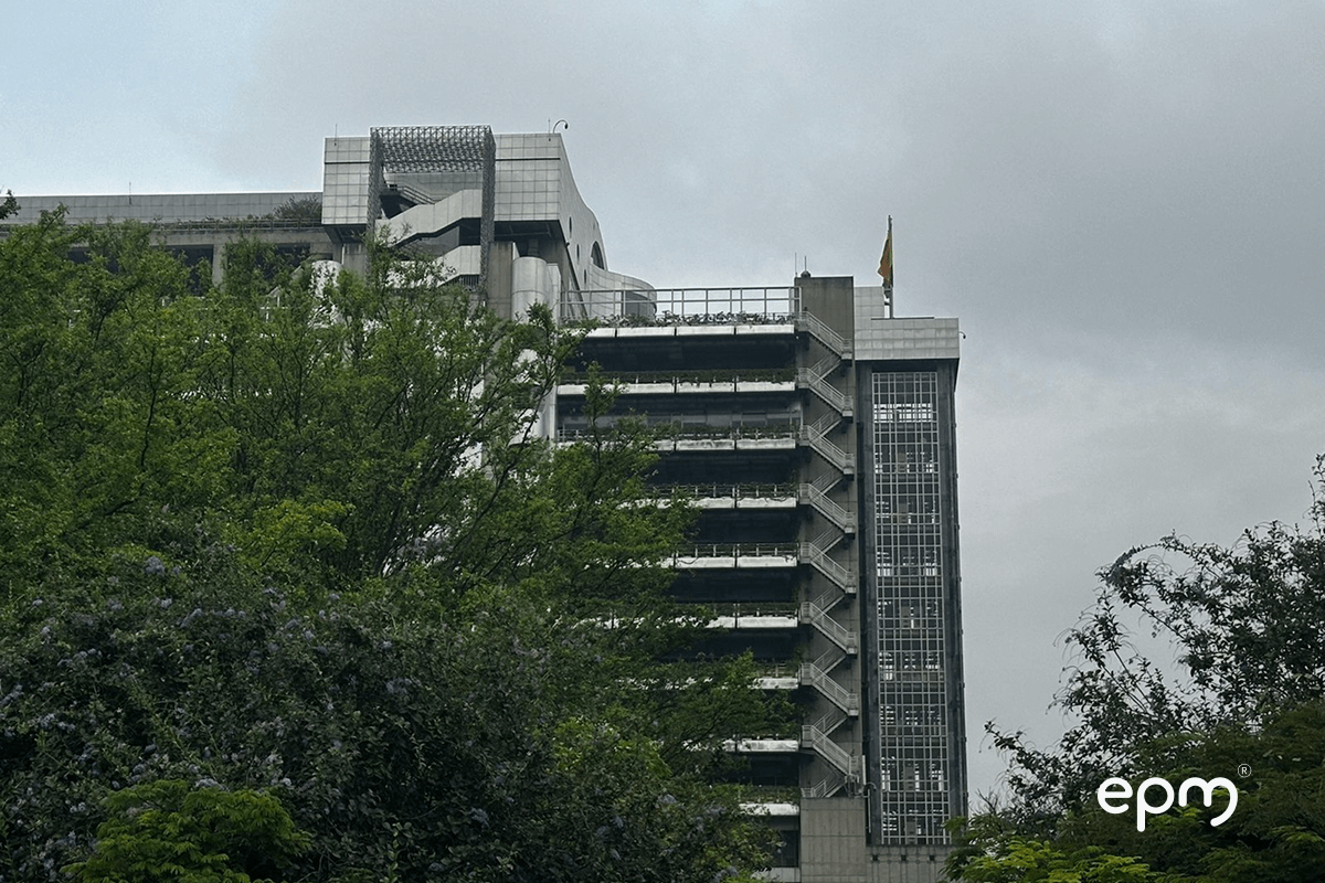 Fotografía de la fachada del edificio inteligente de EPM en Medellín, rodeado de árboles y bajo un cielo nublado.
