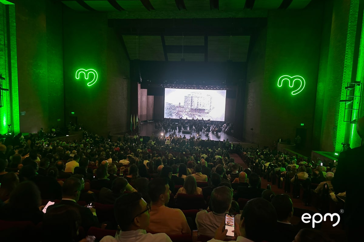 Gran audiencia en un evento, con un escenario iluminado en verde y una pantalla gigante en el fondo, en la celebración de los 70 años de EPM