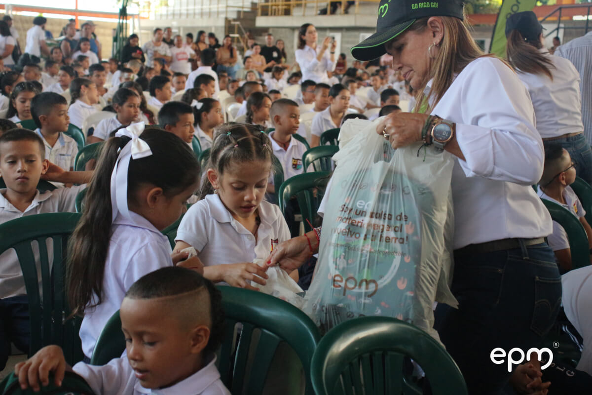 Mujer entregándole kits escolares a niños.