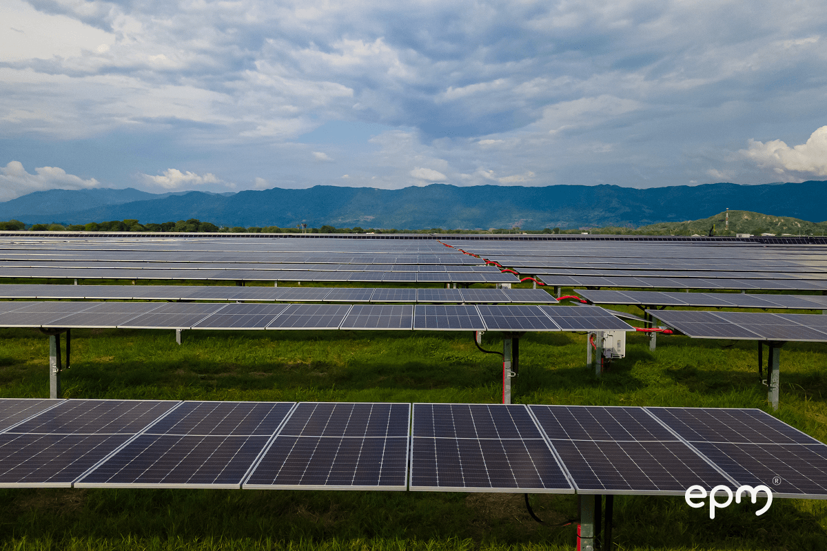 Fotografía de campo de paneles solares de EPM en un entorno rural, con montañas al fondo y cielo parcialmente nublado.