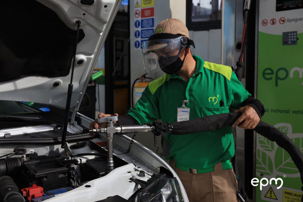 Fotografía de trabajador con uniforme de EPM y equipo de seguridad cargando gas natural vehicular 