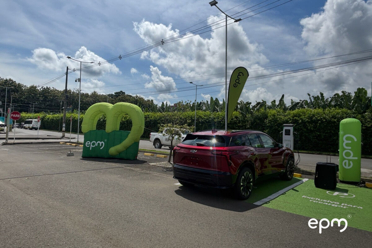 Estación de carga EPM en Urabá con vehículo eléctrico rojo y elementos de marca.