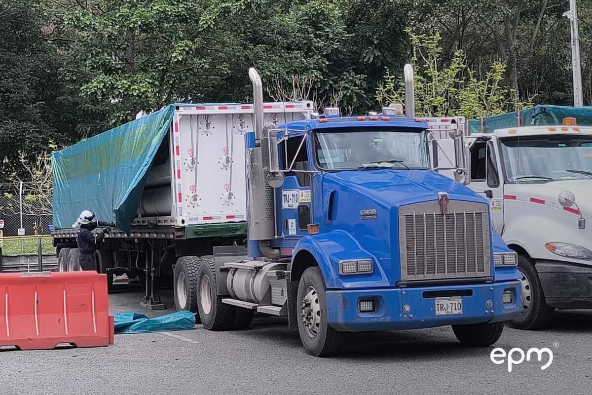 Tractomula de color azul con trailer de color blanco. Se observa funcionario revisando el vehículo
