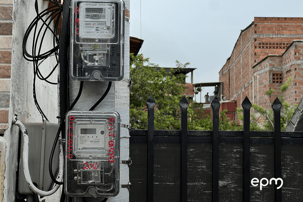 Fotografía de medidores eléctricos instalados en postes del servicio público en zona urbana, con carcasa transparente reciclada.