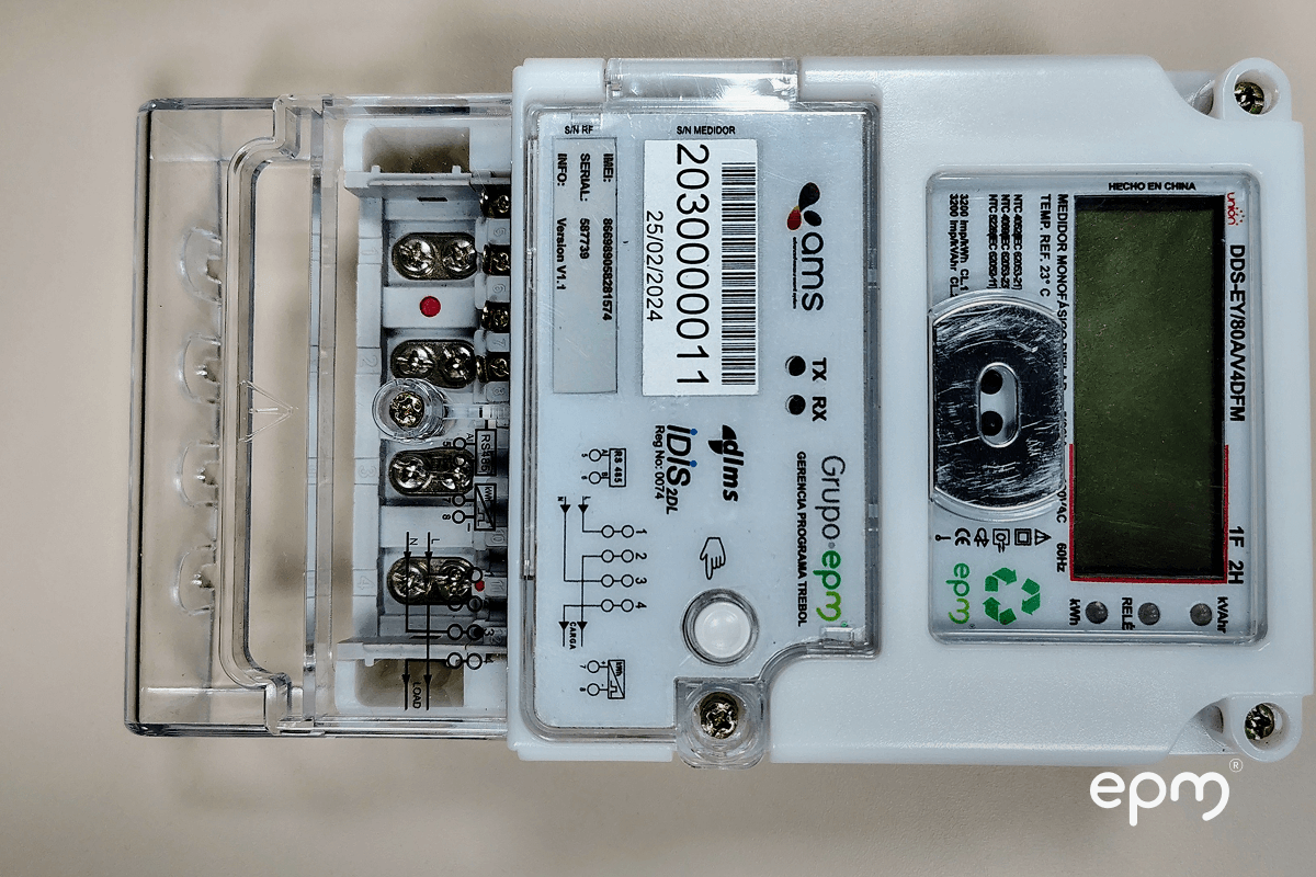 Fotografía de un medidor eléctrico inteligente de EPM fabricado con plástico reciclado, vista de componentes internos y etiqueta con número de serie.