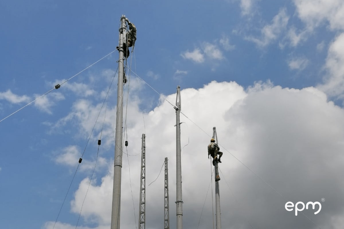 Dos trabajadores de epm sobre unos postes eléctricos realizando mantenimientos