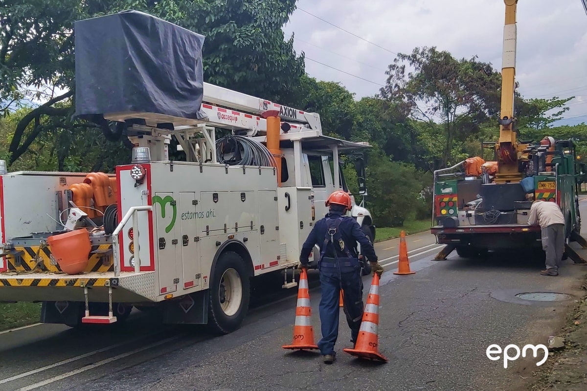 Un trabajador de EPM baja conos viales de una camioneta y los coloca sobre la carretera para señalizar una zona de mantenimiento eléctrico en la vía.
