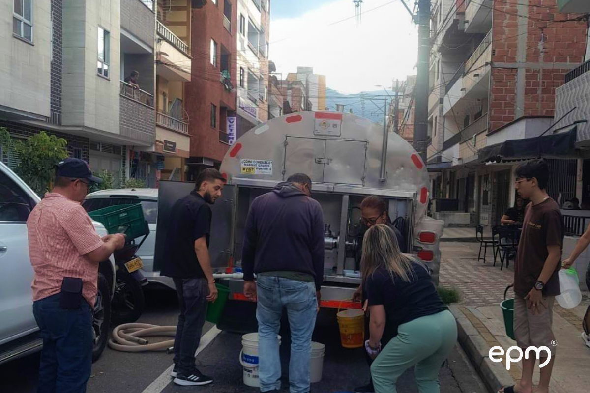 Personas recogen agua en recipientes desde un carrotanque en la calle