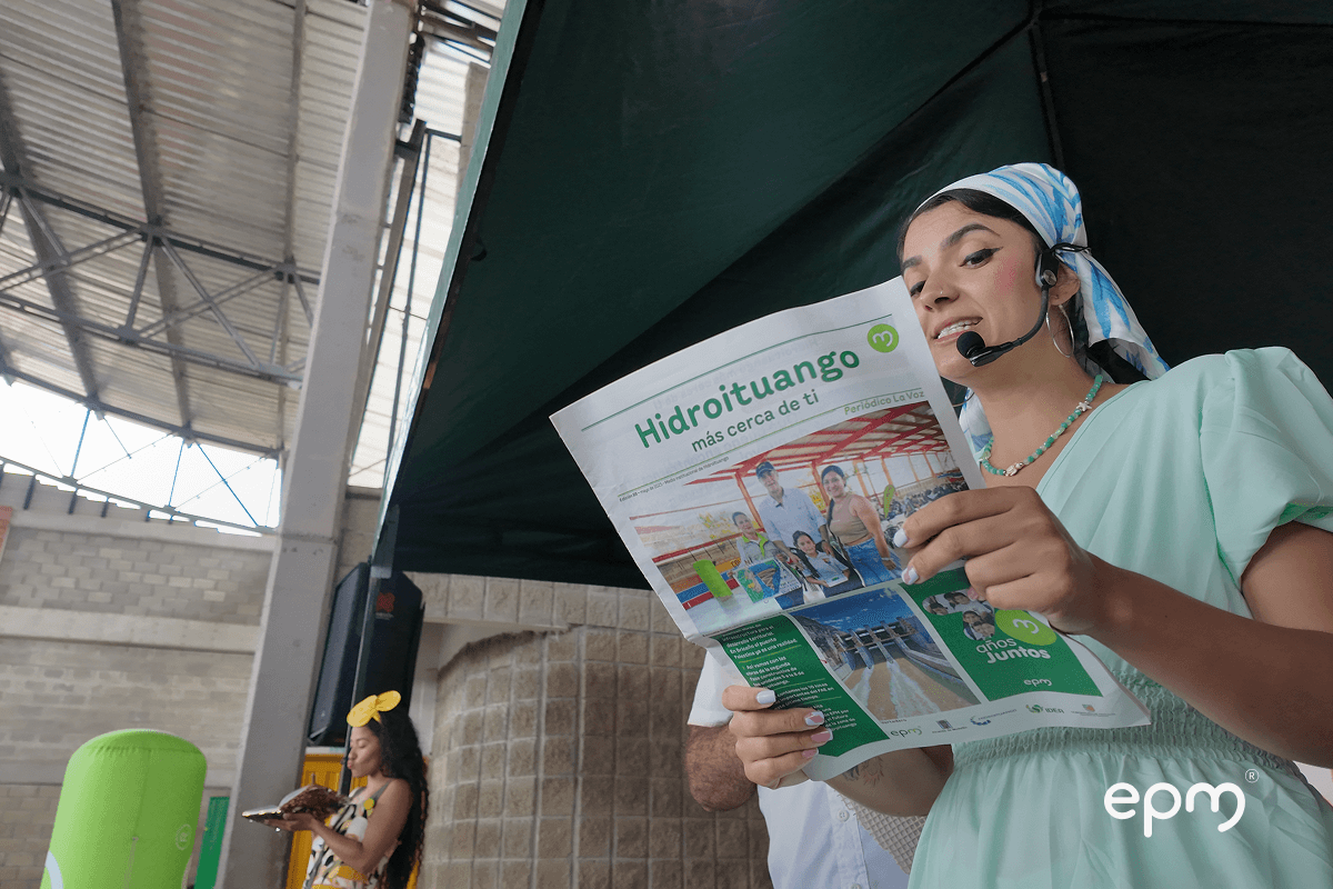 Fotografía de actriz lee periódico “Hidroituango más cerca de ti” durante jornada educativa de EPM en el marco de la Semana Ambiental.