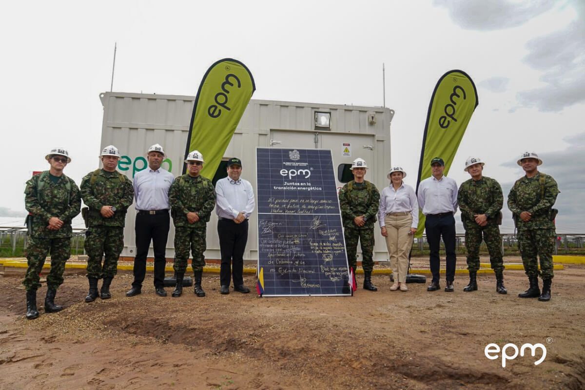 Fotografía de Representantes de EPM y oficiales del Ejército Nacional de Colombia posan junto a un panel solar firmado y un contenedor con logos de EPM
